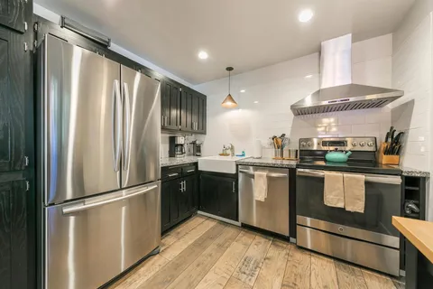 a kitchen with stainless steel appliances granite countertop a sink refrigerator and cabinets