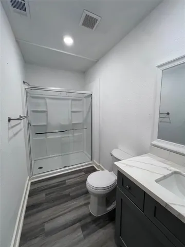 a bathroom with a sink a toilet a shower and a window