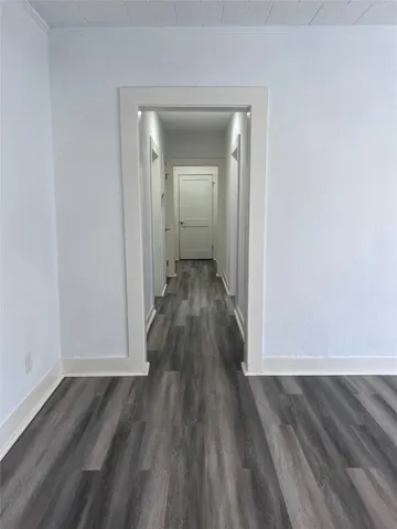 a view of a hallway with wooden floor and a wall