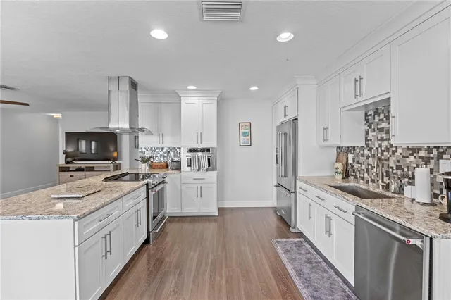 a large kitchen with granite countertop a large counter top space a sink a window and living room