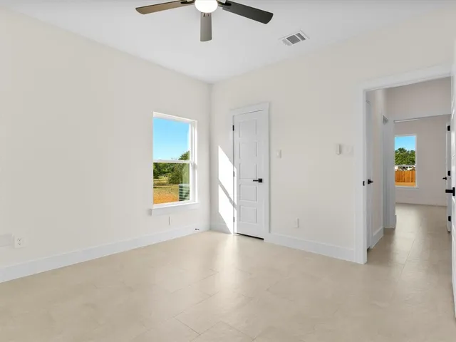 an empty room with fan and windows