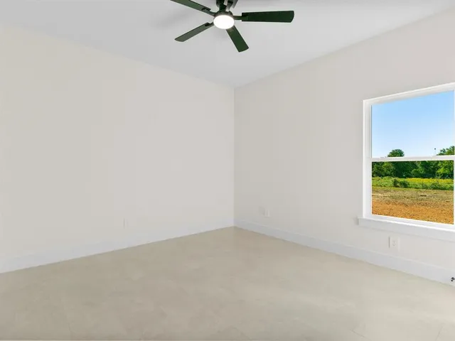 an empty room with a window and a ceiling fan