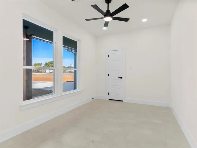 an empty room with a window and a ceiling fan