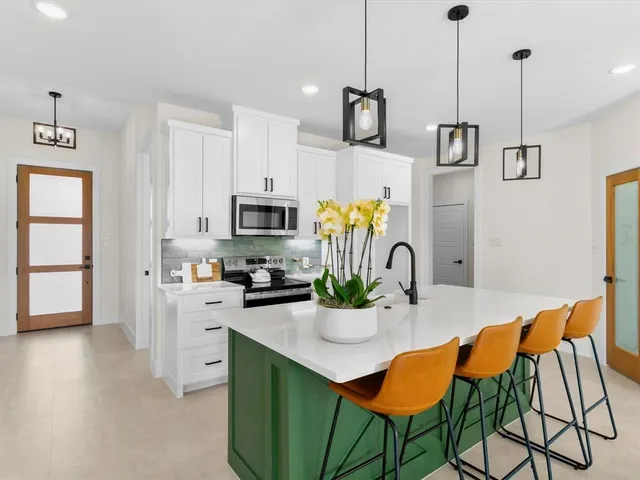 a kitchen with stainless steel appliances kitchen island granite countertop a table chairs and a stove
