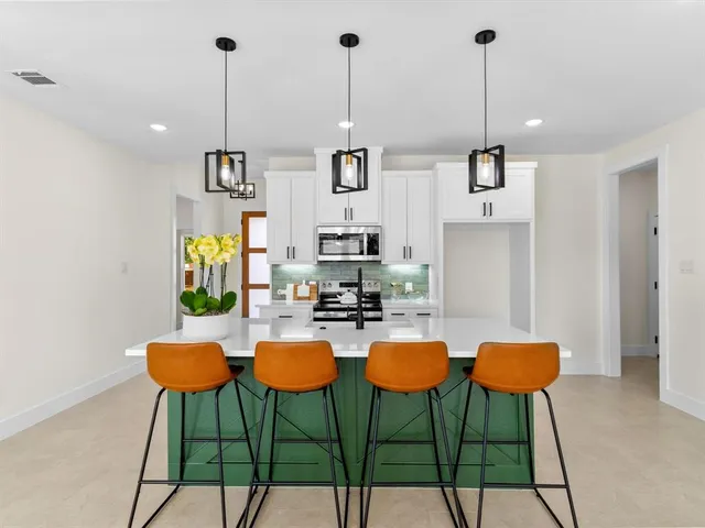 a kitchen with stainless steel appliances kitchen island granite countertop a table chairs and white cabinets