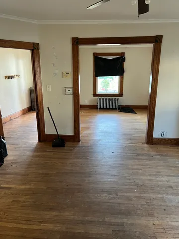 a view of a hallway to an empty room and wooden floor