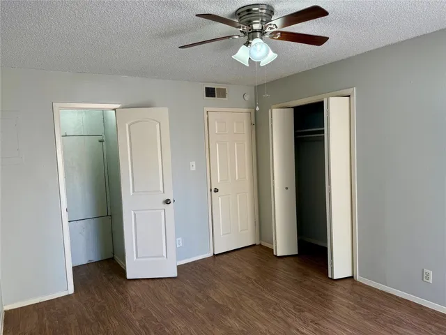 an empty room with wooden floor and ceiling fan