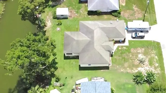 an aerial view of a house with swimming pool and large trees
