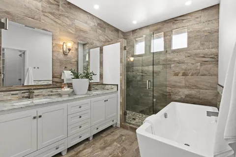 a bathroom with a granite countertop sink mirror and bathtub