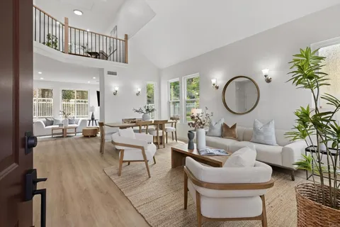 a living room with furniture a rug a lamp and a large window