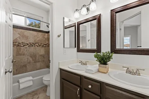 a bathroom with a granite countertop sink a toilet a mirror and shower
