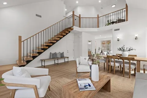 a living room with couches a coffee table and a dining table with wooden floor