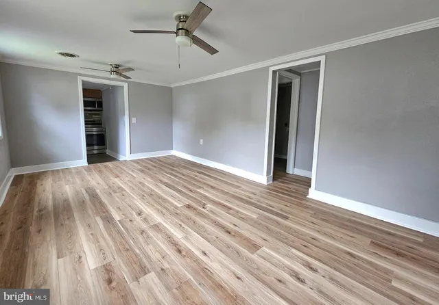 a view of empty room with wooden floor and ceiling fan