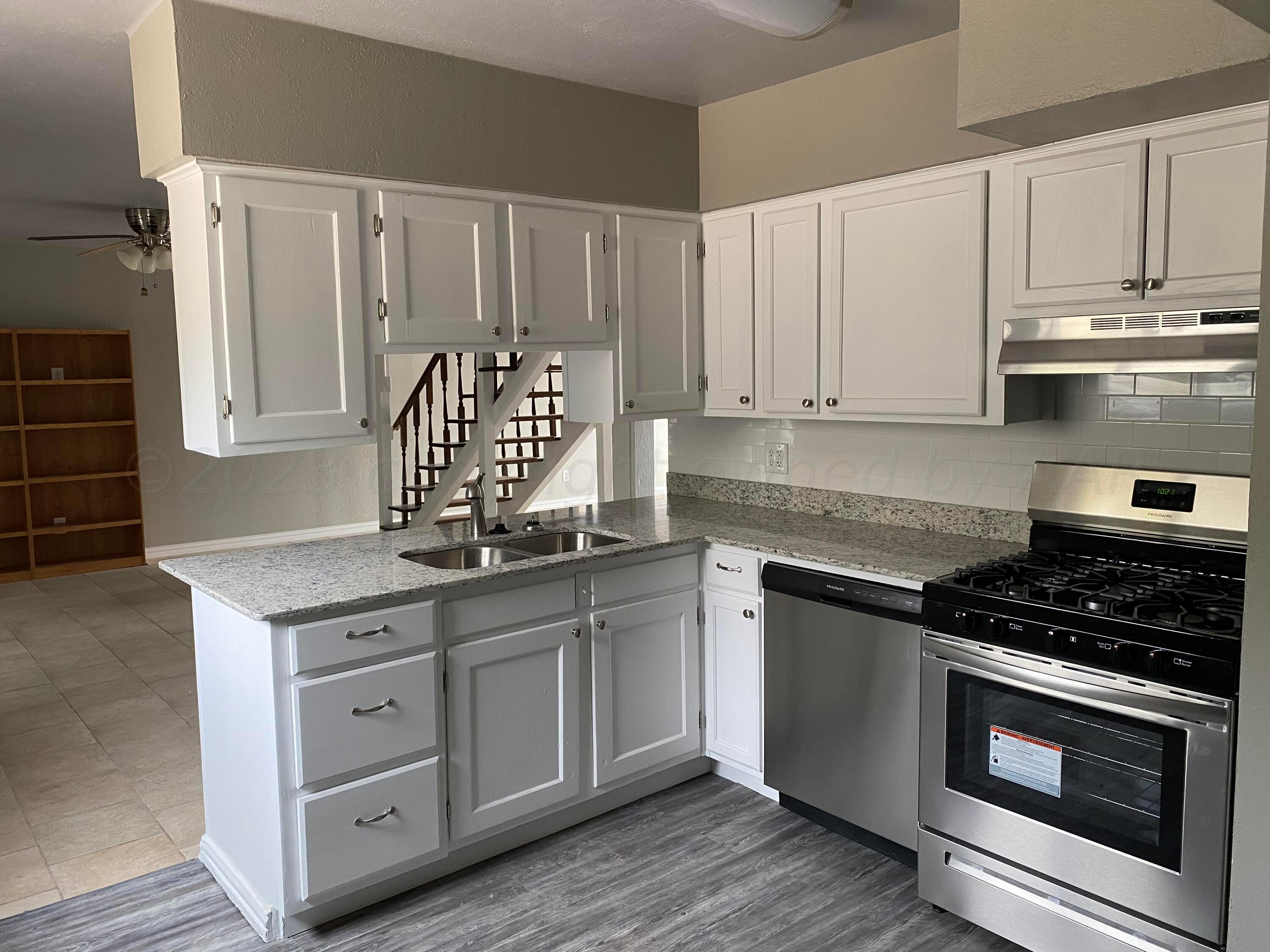 4700 Oregon Trail Amarillo, TX 79109 - Photo 4 of 9 a kitchen with granite countertop white cabinets and stainless steel appliances