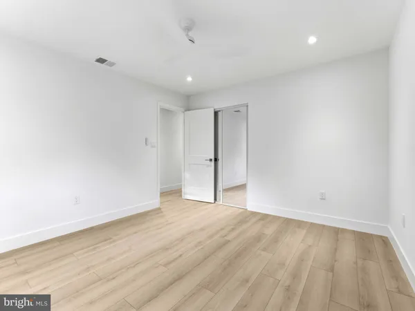 an empty room with wooden floor and mirror