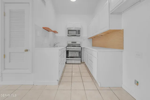 a kitchen with stainless steel appliances a stove and a white cabinet