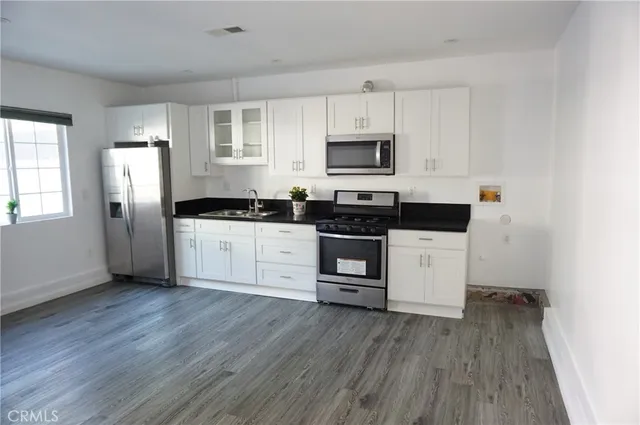 a kitchen with granite countertop cabinets stainless steel appliances and wooden floor