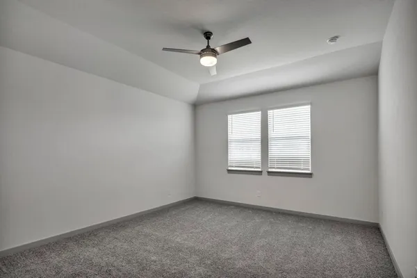 an empty room with ceiling fan and windows