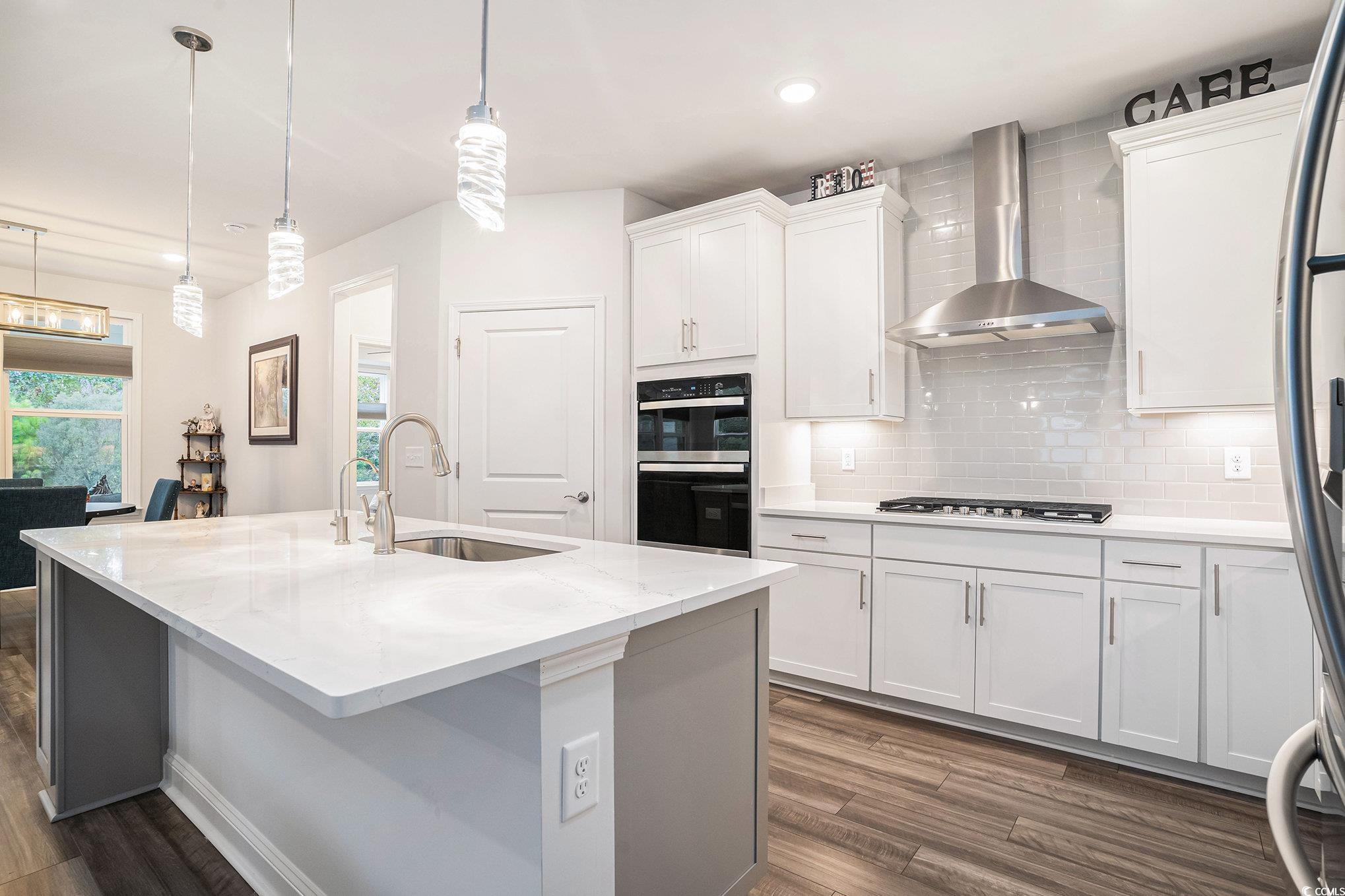 1609 Littleleaf Loop North Myrtle Beach, SC 29582 - Photo 9 of 40 Kitchen with backsplash, decorative light fixtures, wall chimney exhaust hood, dark wood finished floors, and white cabinetry