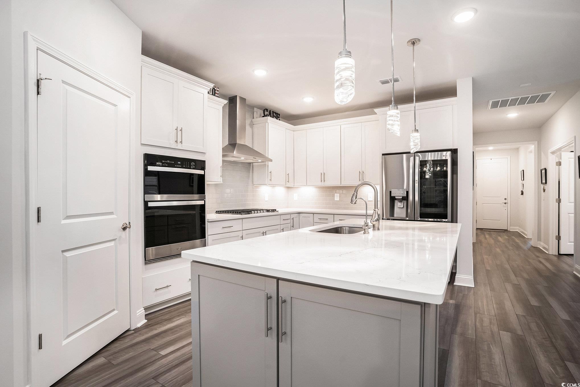 1609 Littleleaf Loop North Myrtle Beach, SC 29582 - Photo 10 of 40 Kitchen with tasteful backsplash, dark wood-style floors, stainless steel appliances, a center island with sink, and wall chimney range hood