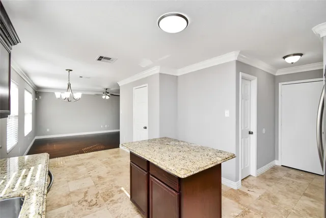 a kitchen that has a kitchen island wooden cabinets and refrigerator
