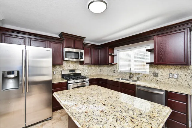a kitchen with stainless steel appliances granite countertop a sink stove microwave and refrigerator