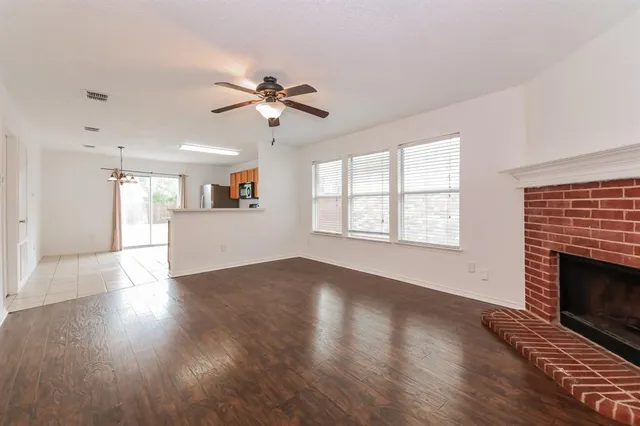 a view of an empty room with wooden floor and a fireplace