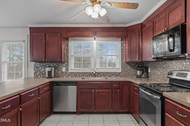 a kitchen with stainless steel appliances granite countertop a sink stove microwave and refrigerator