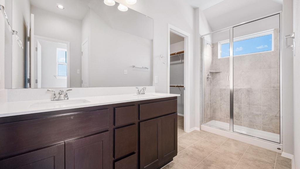 208 Stein Road Georgetown, TX 78626 - Photo 17 of 30 Bathroom featuring a stall shower, double vanity, a walk in closet, and tile patterned flooring