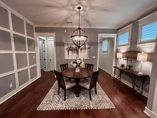 498 South Shea Road Collierville, TN 38017 - Photo 11 of 17 Dining space with crown molding, dark wood-type flooring, visible vents, a notable chandelier, and baseboards