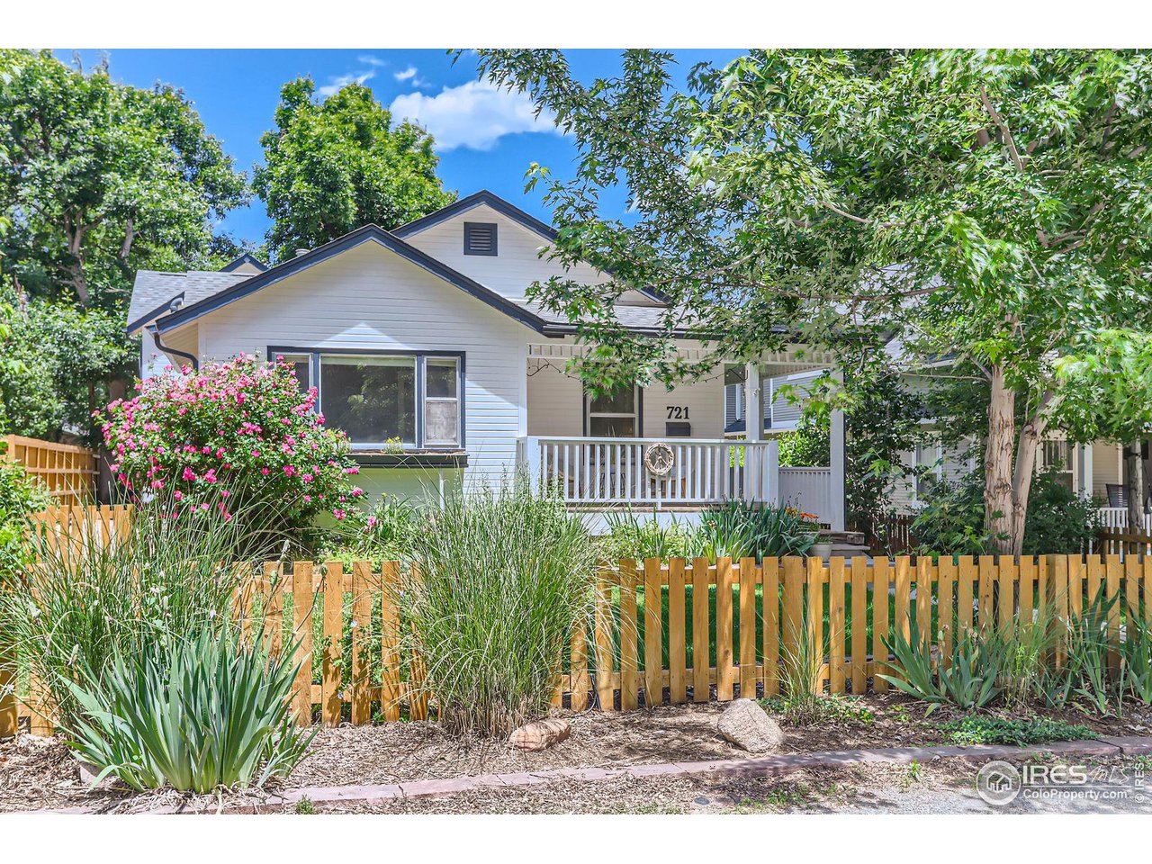 a house that has a tree in front of it with wooden fence