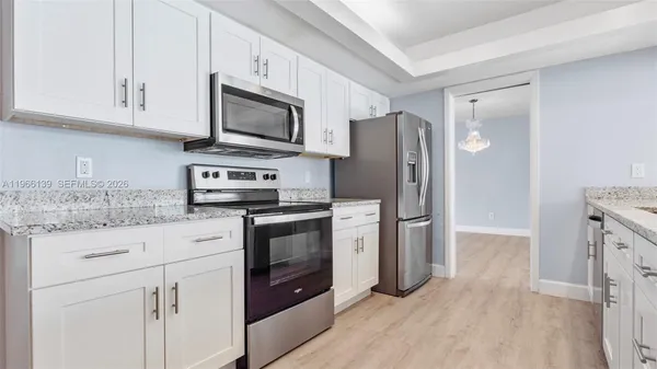 a kitchen with stainless steel appliances granite countertop a refrigerator stove and white cabinets