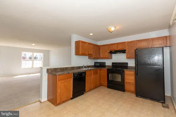 a kitchen with stainless steel appliances granite countertop a refrigerator a sink dishwasher a stove with wooden cabinets