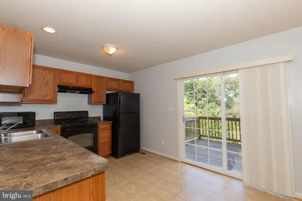 a kitchen with stainless steel appliances granite countertop a refrigerator a stove and a sink with wooden floor