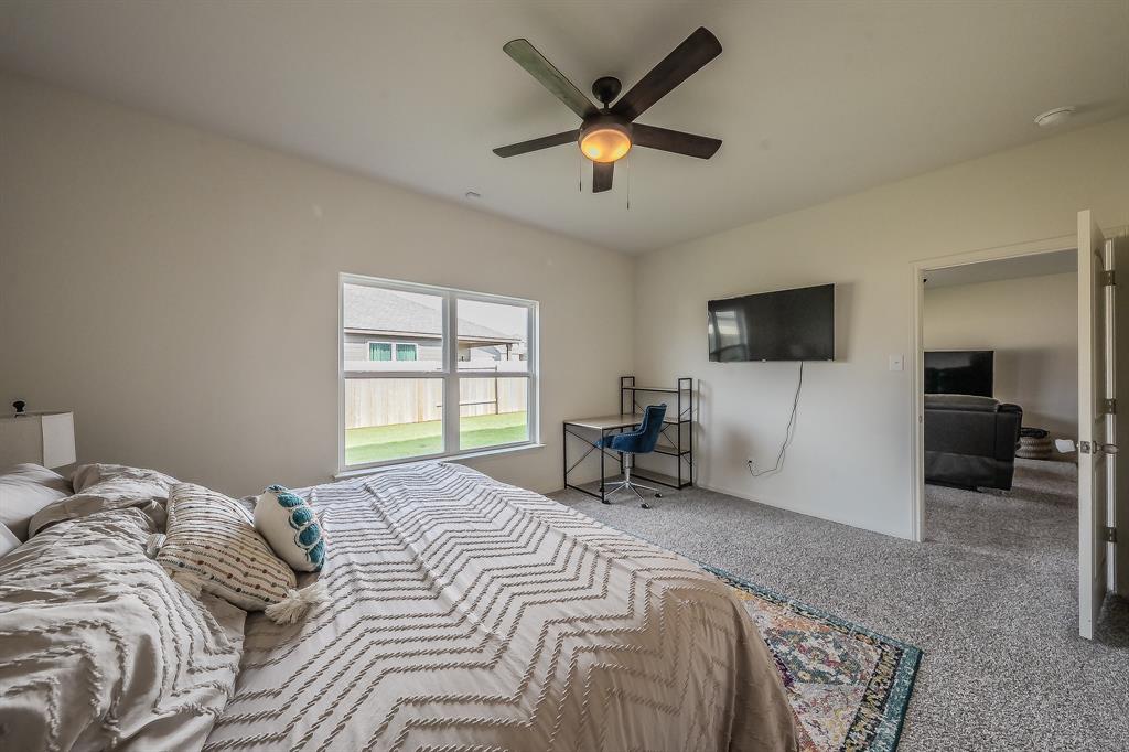 8125 White Sulphur Road Ponder, TX 76259 - Photo 14 of 38 Bedroom featuring light gray wall paint, gray carpeting, a multi-pane window, and a ceiling fan with integrated lighting