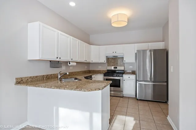 a kitchen with stainless steel appliances granite countertop a refrigerator a stove a sink and a granite counter tops