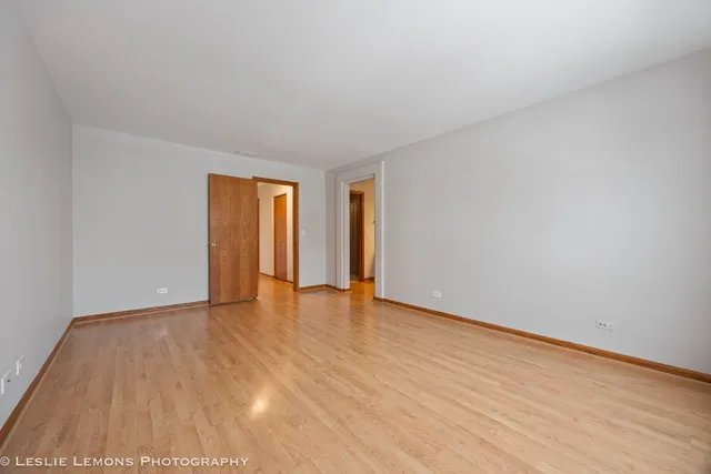 a view of an empty room with wooden floor and window