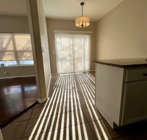 an empty room with wooden floor fire place and windows