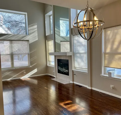 an empty room with wooden floor fireplace and windows
