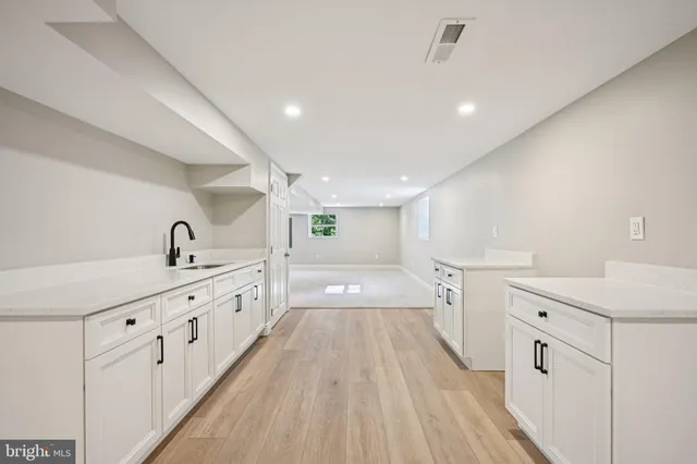 a large white kitchen with a lot of counter space and wooden floor