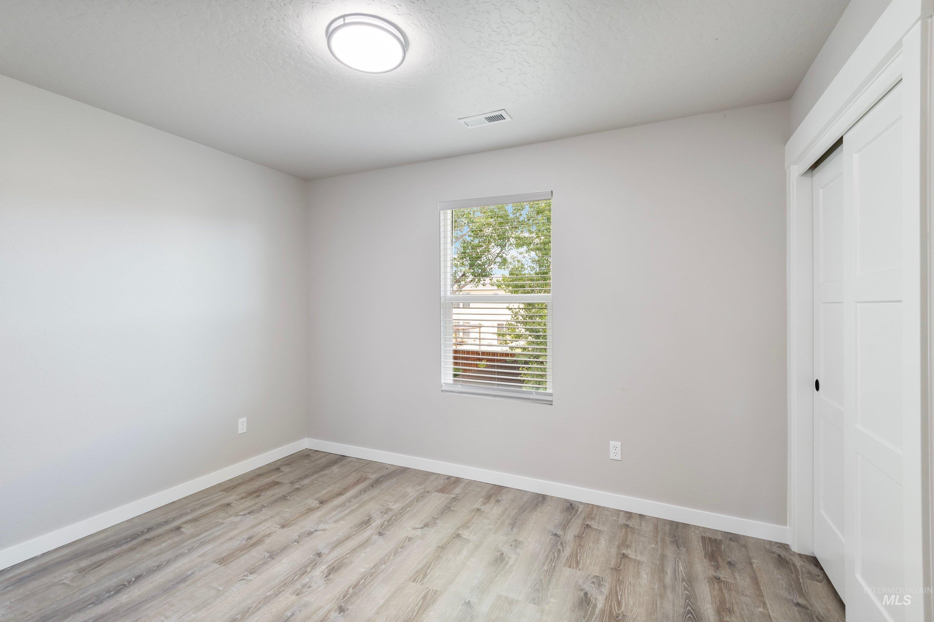 16759 Abram Avenue Caldwell, ID 83607 - Photo 18 of 33 Bright room featuring wood-finish flooring, a window with blinds, a ceiling-mounted light fixture, and a sliding closet door