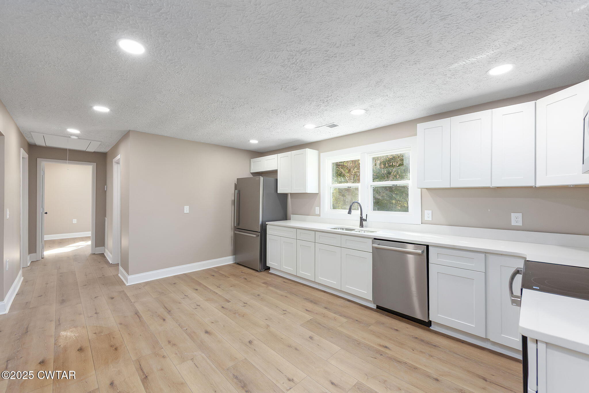424 Rozelle Street Gibson, TN 38343 - Photo 6 of 20 a large white kitchen with wooden floor and stainless steel appliances