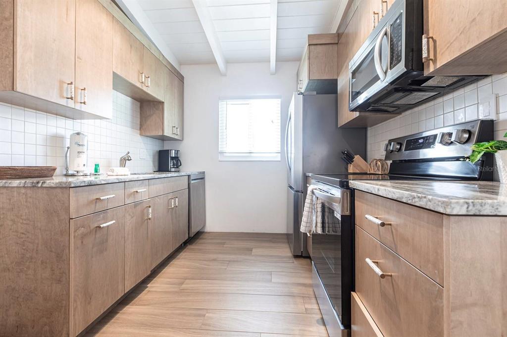 6006 Midnight Pass Road, Unit 53 Sarasota, FL 34242 - Photo 6 of 20 a kitchen with stainless steel appliances granite countertop a sink a stove and a refrigerator