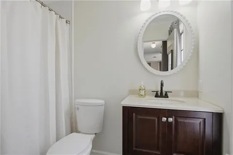 a bathroom with a granite countertop sink a toilet and a mirror