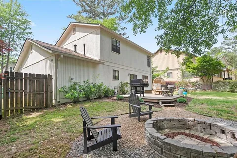a view of a backyard with table and chairs potted plants and a large tree