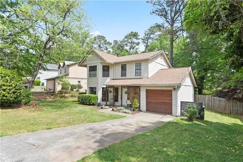 a front view of a house with a garden and trees