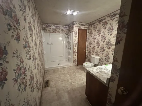 a bathroom with a granite countertop sink a toilet and shower
