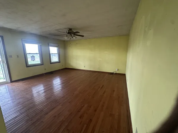an empty room with wooden floor and windows