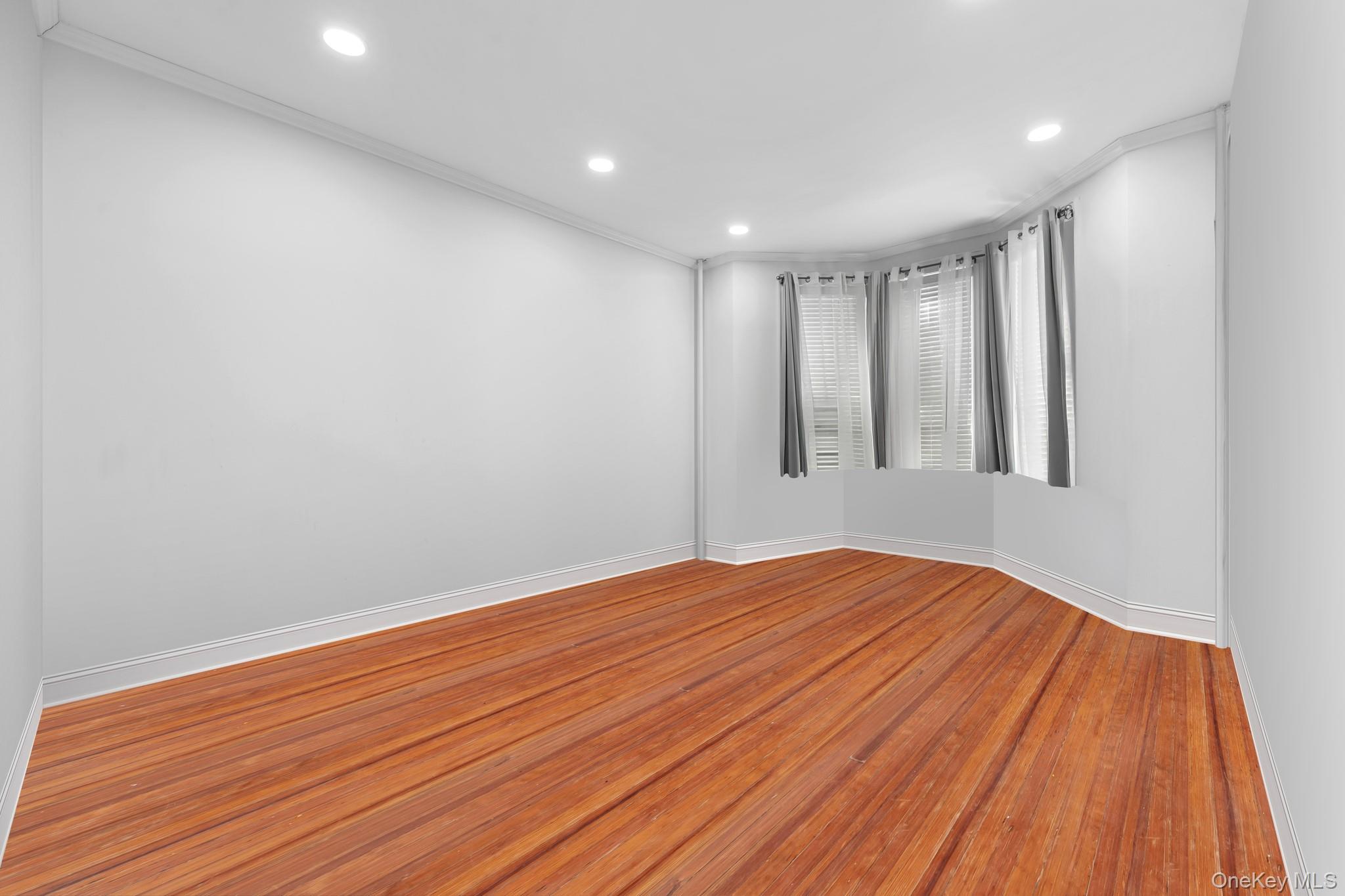 103-17 Plattwood Avenue Queens, NY 11417 - Photo 11 of 25 a view of empty room with wooden floor and fan