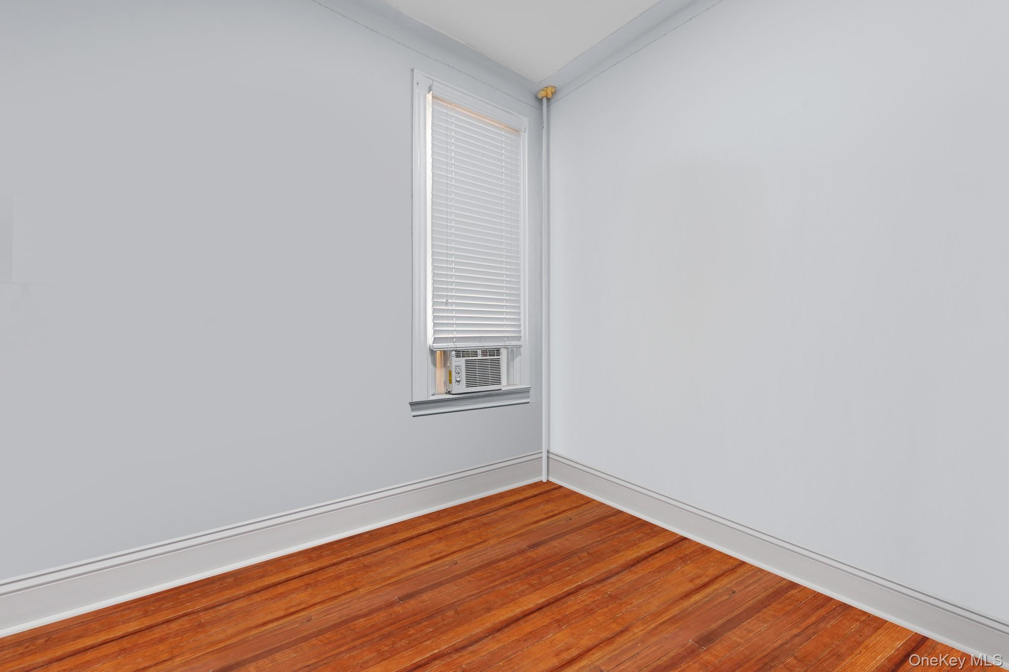 103-17 Plattwood Avenue Queens, NY 11417 - Photo 20 of 25 a view of an empty room with wooden floor and a window